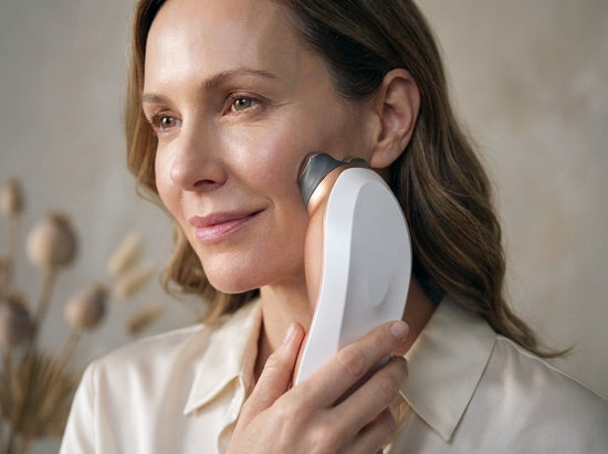 Woman using RF device on cheek, skincare beauty routine, neutral background